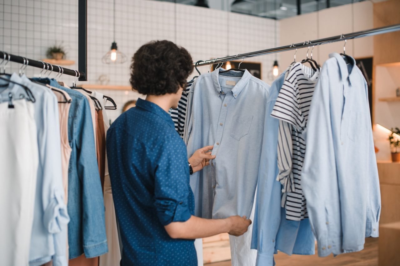 stylish young man choosing fashionable shirts in boutique.jpg